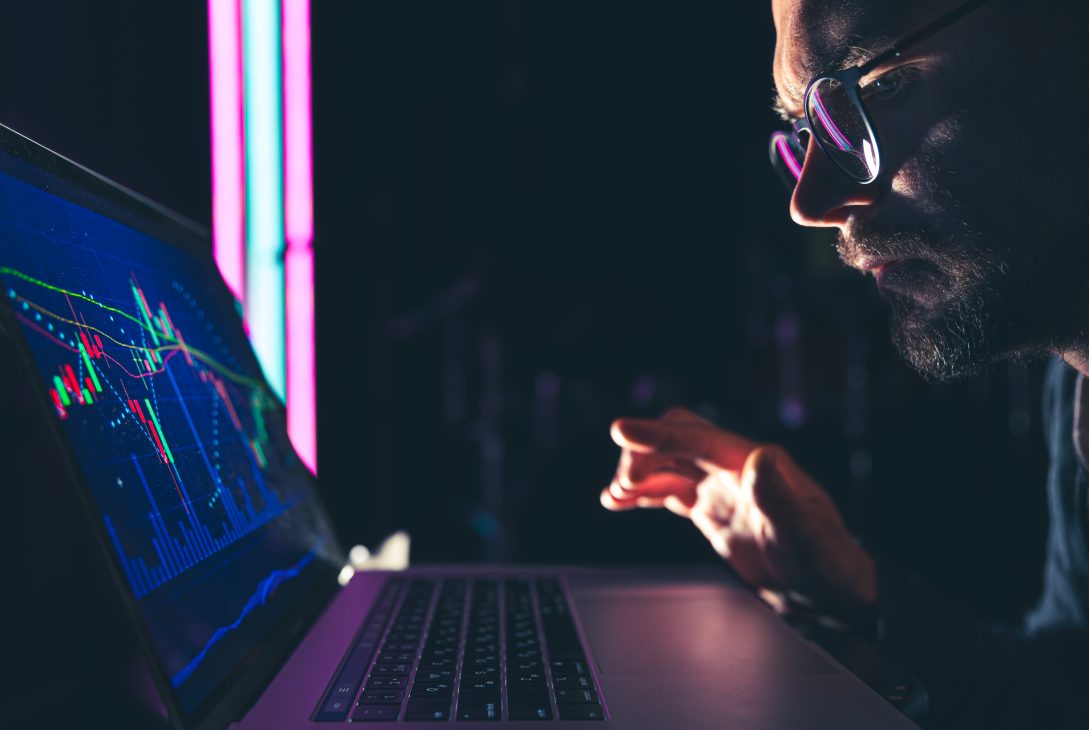 A man analyzing stock market charts, financial data on an electronic board.