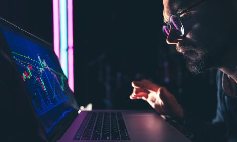 A man analyzing stock market charts, financial data on an electronic board.